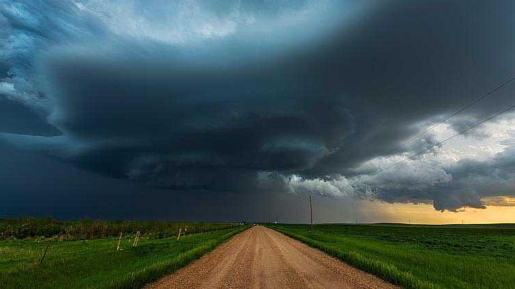 Dark storm clouds above a rural road and fields that have the potential to spawn a tornado.