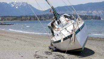 A beached sailboat rests on its side.